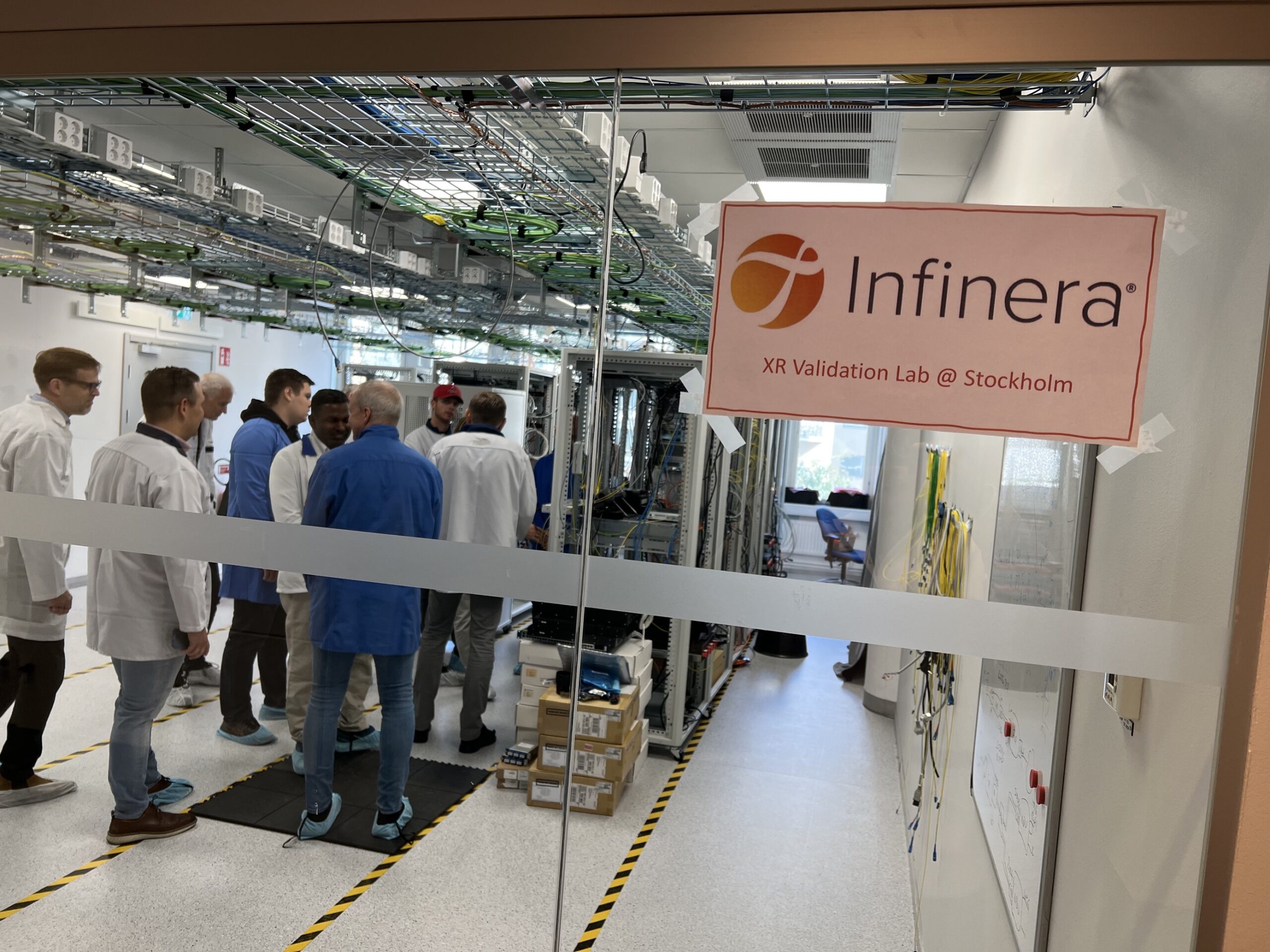 En gruppe mennesker bak glassdør hos Infinera XR Validation Lab i Stockholm.